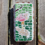 Spoonbill Reflecting A mosaic of a pink spoonbill and its refection. Mosaic is made with ceramic tile. It is wall art that is fastened to a wood fence.