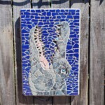 Big Ole Gator a mosaic wall hanging of an alligator's head coming straight out of the water. The piece is 18.5" x 12.5" x 1". Blue and grey are the primary tile colors